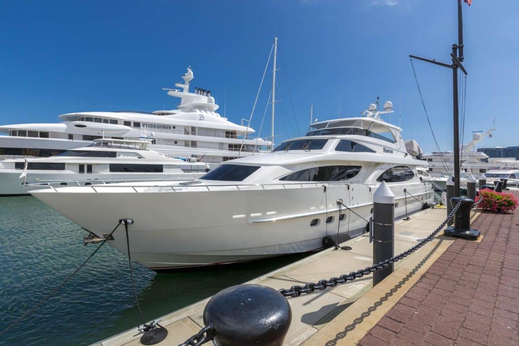 Yacht Dockage White luxury yacht docked at a modern, upscale marina under a clear blue sky.